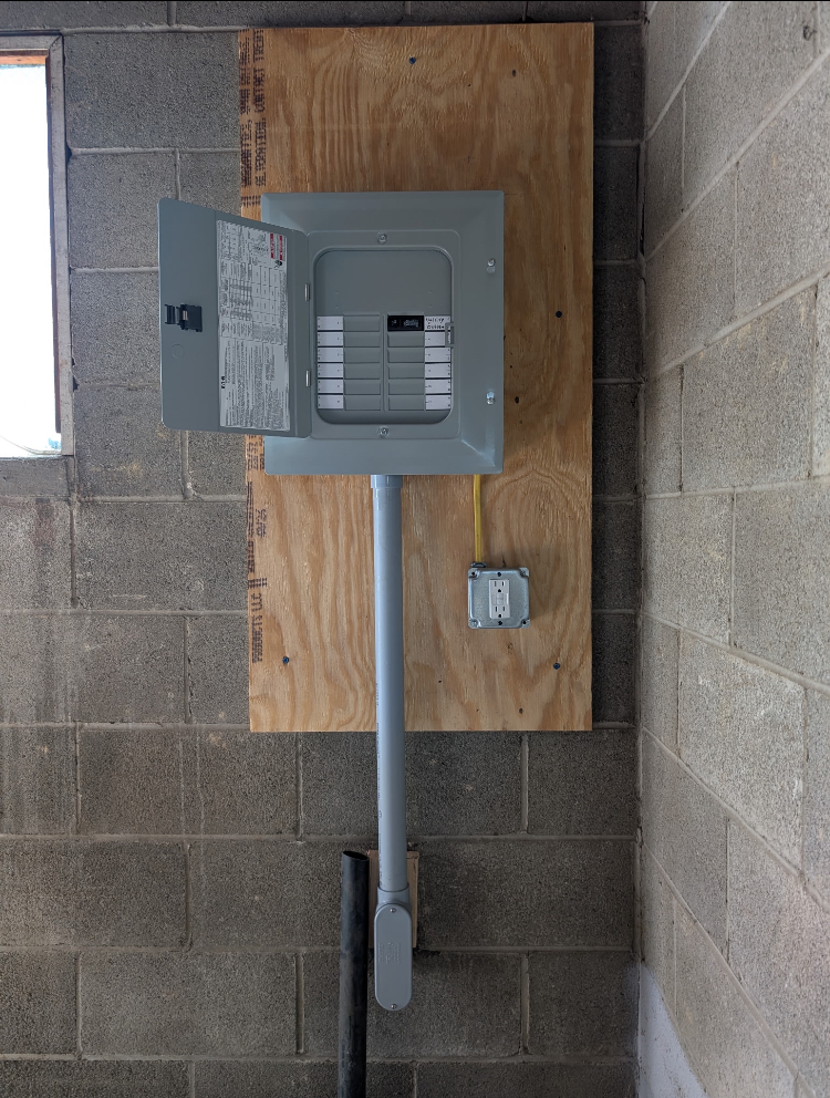 A new sub-panel mounted on a plywood backer with a dedicated GFCI outlet and conduit run to grade
